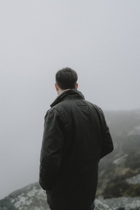 Male hiker in jacket looking away into fog