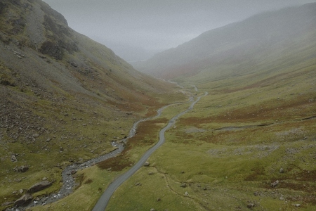 Aerial view road along winding stream in remote landscape