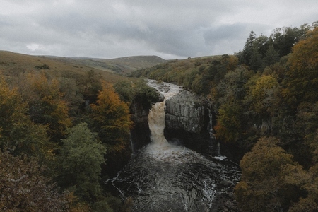 Waterfall over rocks in remote autumn landscape