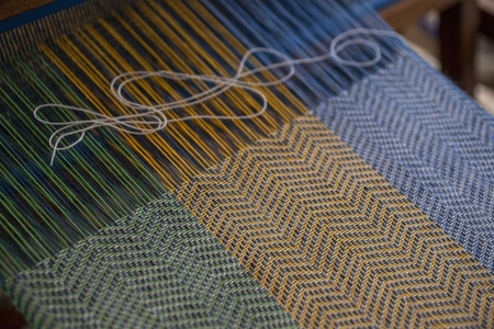 Blue green and orange thread on loom