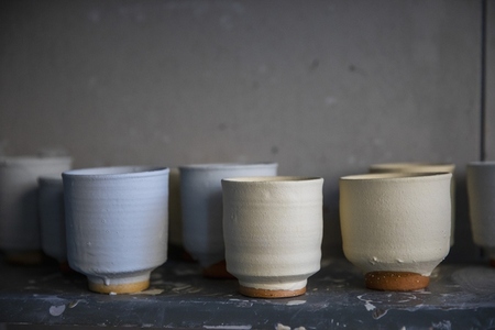 Clay pottery cups drying on shelf