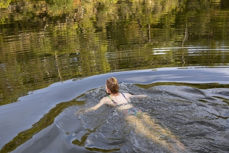 Carefree woman swimming in tranquil summer river