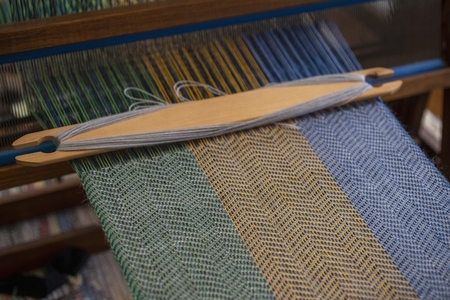 Blue green and orange thread forming pattern on loom