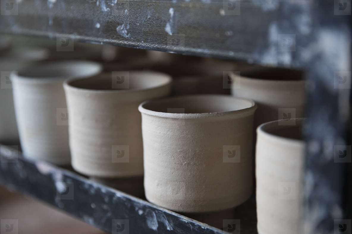 Close up thrown clay cups drying in a row