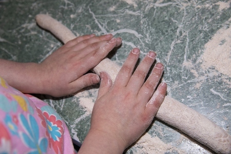 Close up view from above hands of girl rolling dough