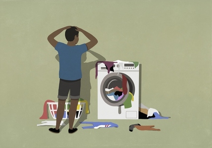 Frustrated man looking at laundry piled up on washing machine