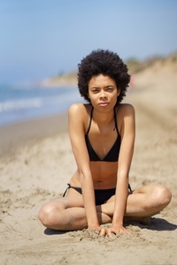Black woman in bikini on sandy seashore