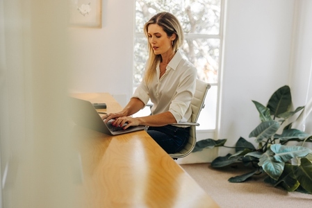 Modern businesswoman typing on a laptop in her office