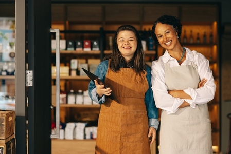 Two successful shop employees smiling at the camera happily