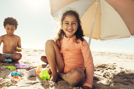 Happy young girl playing with her toys at the beach