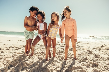 Cheerful kids playing together on beach sand