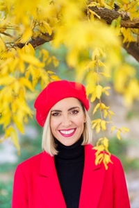 Delighted young blonde in elegant outfit standing near tree in autumn park
