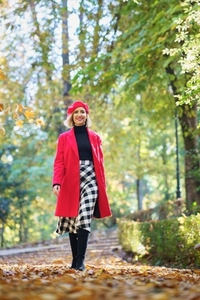 Cheerful woman in coat walking in park