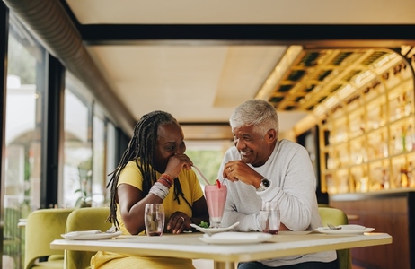 Romantic senior couple sharing a delicious milkshake in a cafe