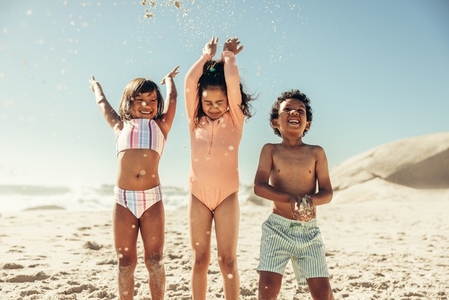 Happy kids throwing beach sand into the air