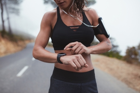Woman adjusting her smartwatch while exercising outdoors