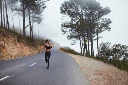 Sporty young woman running along a country road