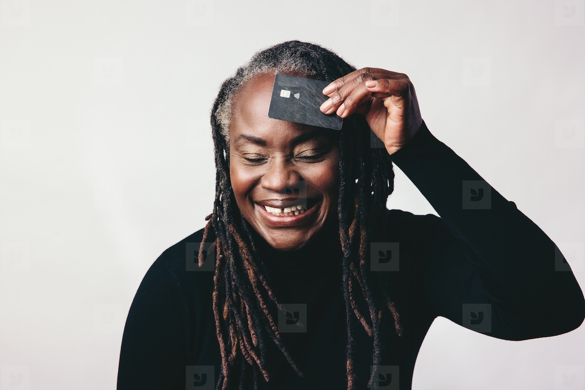 Cheerful mature woman smiling while holding a credit card