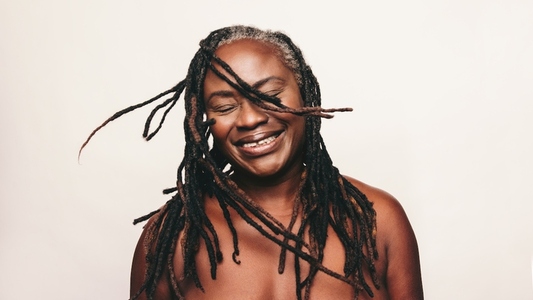 Cheerful woman with dreadlocks smiling in a studio