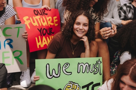 Happy teenage girl sitting with a group of climate activists