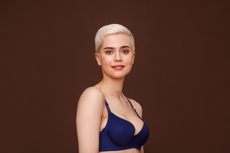 Beautiful blond woman with short hair posing on brown backdrop