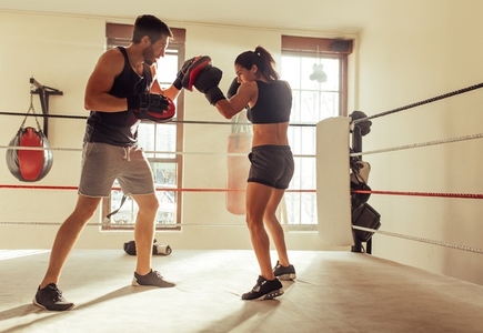 Female boxer practicing punching techniques with her trainer