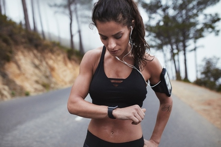 Sporty young woman checking her smartwatch outdoors