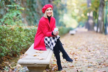 Smiling woman with coffee cup sitting in park