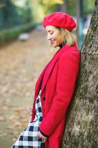 Smiling woman in red outfit and skirt leaning on tree