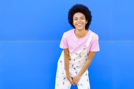 Delighted black woman near blue wall