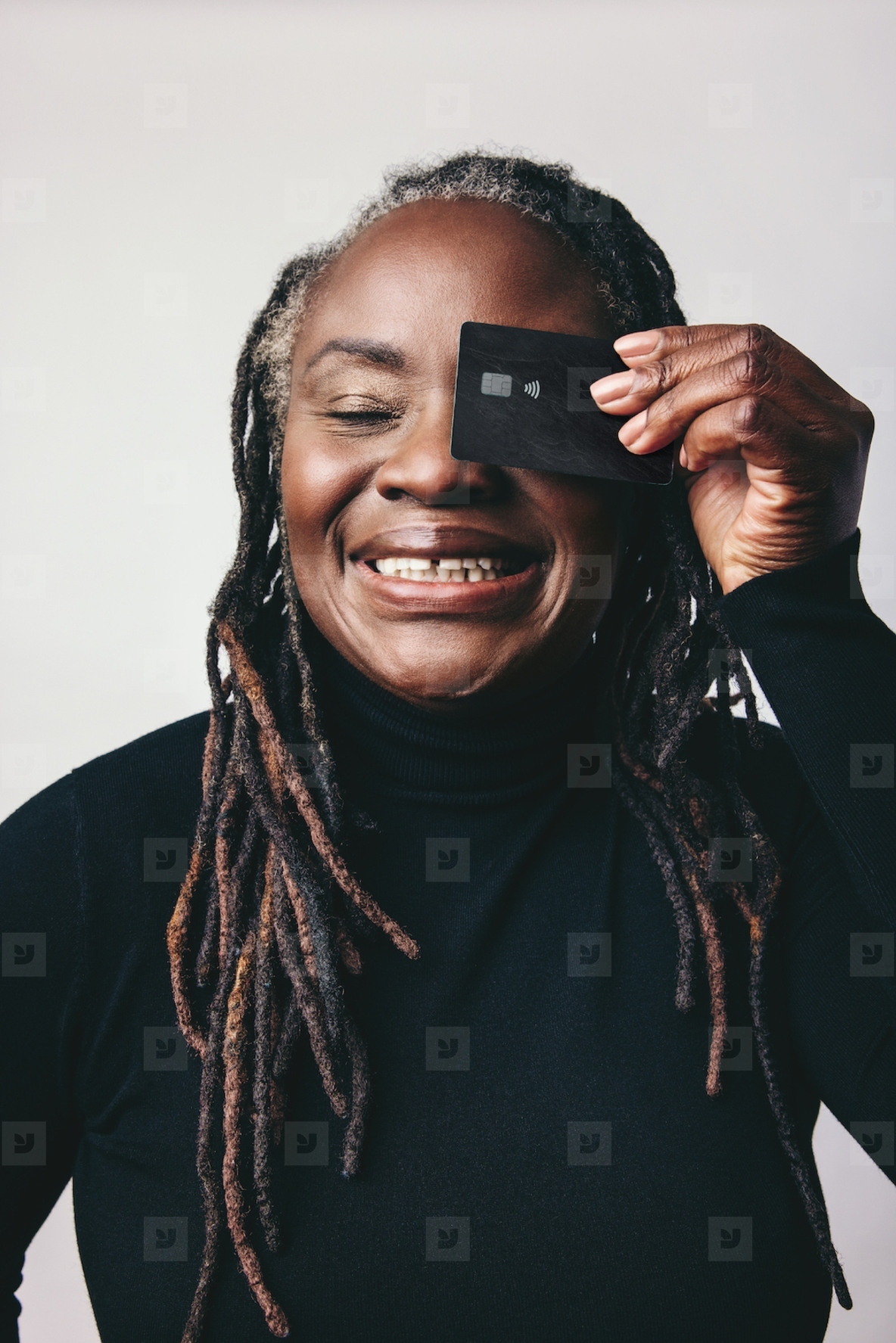Smiling mature woman holding a credit card over her eye