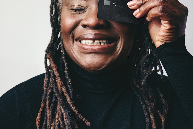 Smiling mature woman holding a credit card over her eye