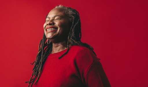 Elegant woman with dreadlocks laughing happily in a studio