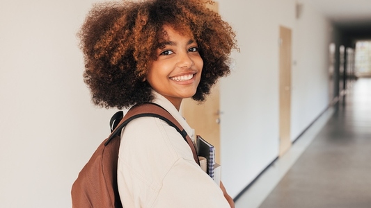 Smiling girl looking back while walking in high school corridor