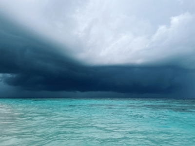 View on a clean ocean water with thunder clouds on horizon