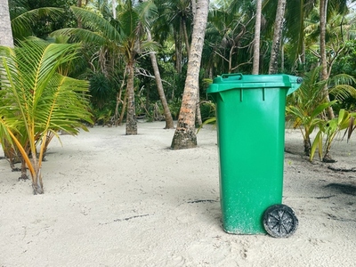 Green garbage bin on a tropical beach
