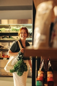 Cheerful young woman grocery shopping in a supermarket