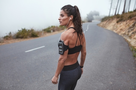 Fit young woman standing on a highway in sportswear