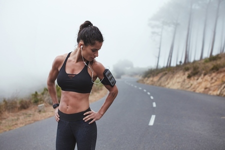 Female athlete having a morning training session long a misty road