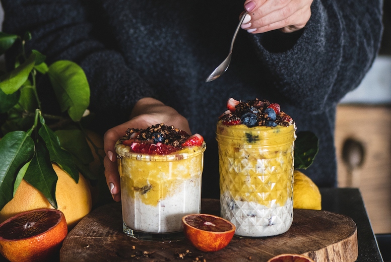 Woman eating healthy muesli with mango smoothie and granola