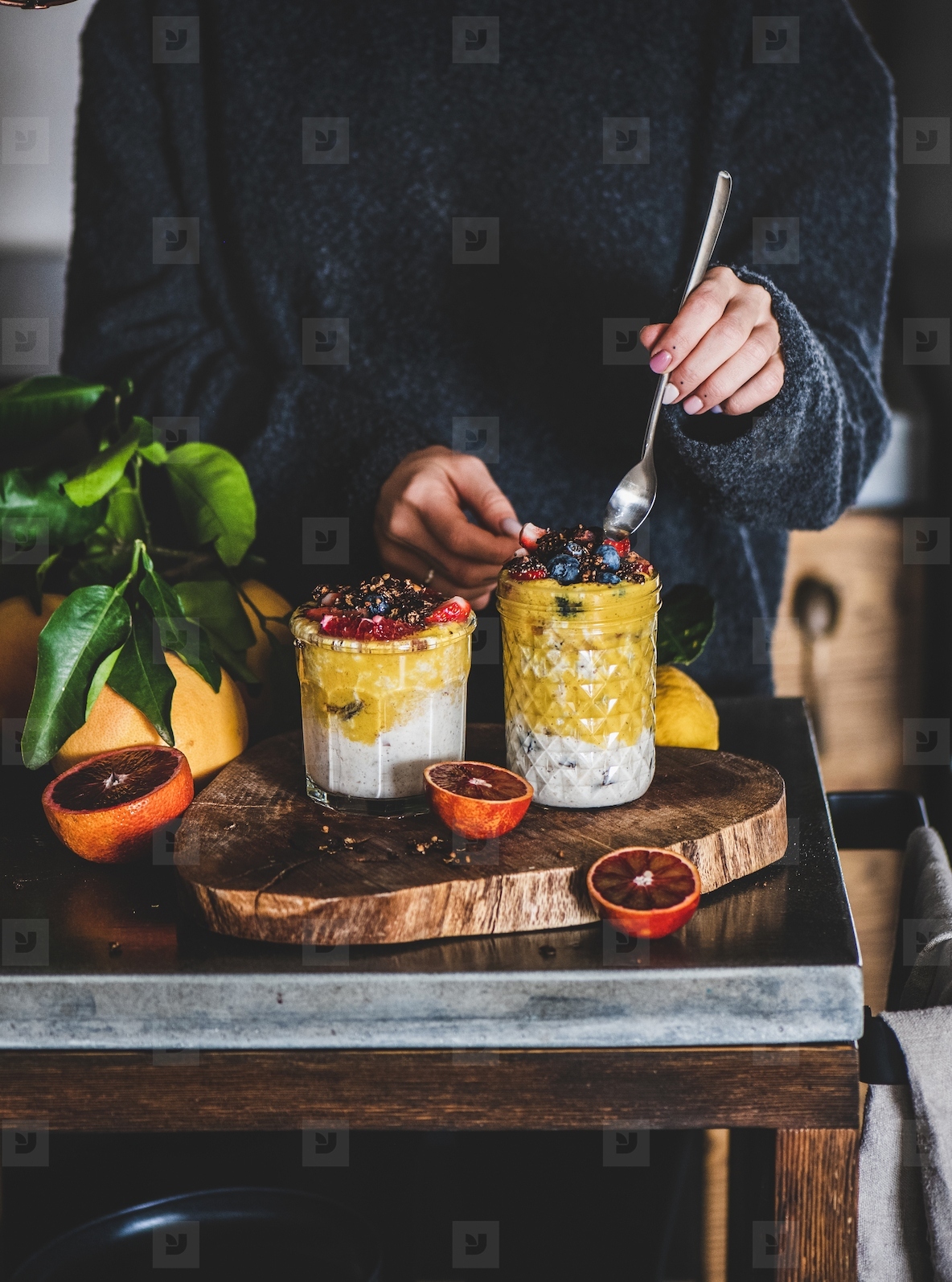 Woman eating muesli with mango smoothie and granola with spoon