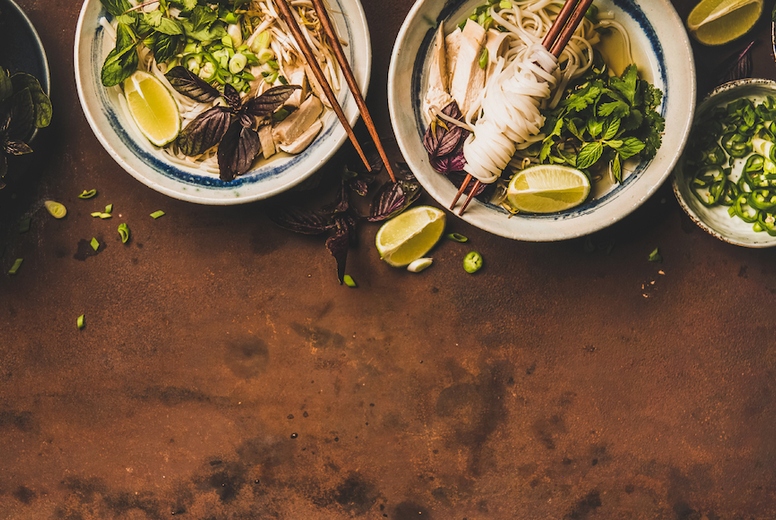 Flat-lay of Vietnamese lunch with soup Pho Ga, wide composition