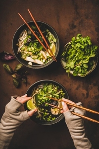 Vietnamese soup Pho Ga and womans hands with chopsticks