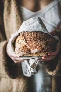 Woman holding healthy rye Swedish bread round loaf in hands
