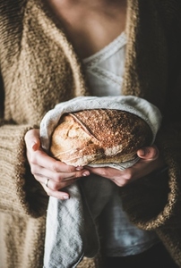 Woman holding healthy wheat Swedish bread round loaf in hands
