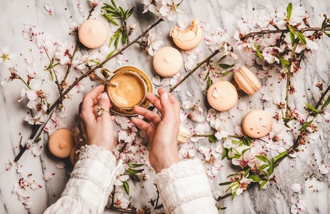 Womans hands over espresso coffee  macaron cookies and flowers