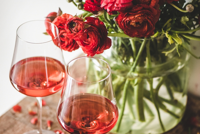 Rose wine in glasses and red spring flowers