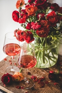 Rose wine in glasses and red spring flowers