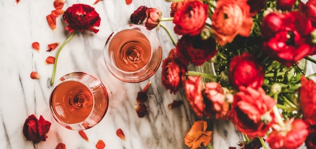 Rose wine in glasses and red spring flowers  wide composition