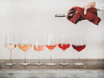Rose wine shades and womans hand pouring wine to glass
